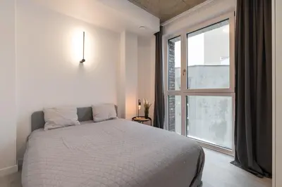 a bedroom with a bed and a large window at Bossa Nova - modern 2 bedroom apartment in the center in Vilnius