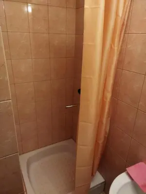 a shower with an orange shower curtain and a toilet at ITAJA apartment in Šiauliai