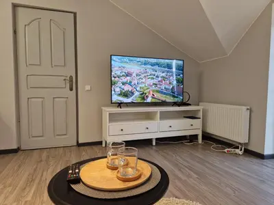 a living room with a flat screen tv and a table at Seliu 25 Homestay Apartment poilsio namai in Šiauliai