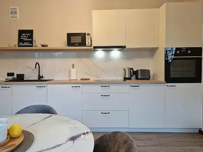 a kitchen with white cabinets and a table at Seliu 25 Homestay Apartment poilsio namai in Šiauliai