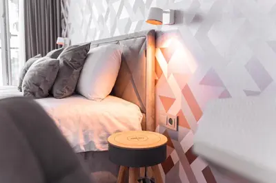 a bedroom with a bed with a stool next to it at Bright Kaunas apartment with Castle view in Kaunas
