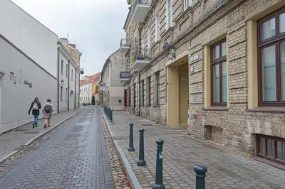 a woman walking down a cobblestone street next to buildings at Modern Vilnius Old Town apartment with free parking in Vilnius