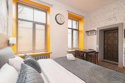 a bedroom with a bed and a desk and a clock at Modern Vilnius Old Town apartment with free parking in Vilnius