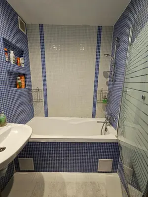 a blue tiled bathroom with a tub and a sink at Apartment Maya in Visaginas