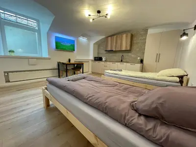 two beds in a large room with a kitchen at Modern guest house in city center I Room 1 in Vilnius