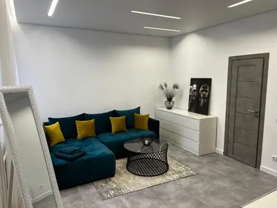 a living room with a blue couch and a table at ADIS Apartments in Druskininkai