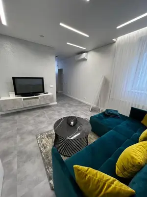 a living room with a blue couch and a tv at ADIS Apartments in Druskininkai