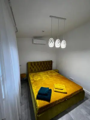 a bedroom with a yellow bed with two towels on it at ADIS Apartments in Druskininkai