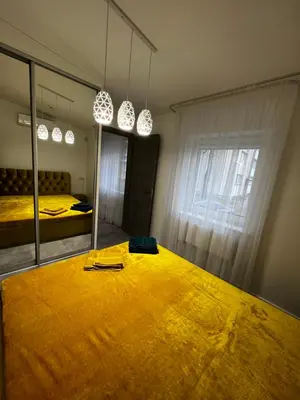 a bedroom with a large yellow bed and a mirror at ADIS Apartments in Druskininkai