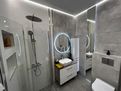 a bathroom with a shower and a sink and a mirror at ADIS Apartments in Druskininkai
