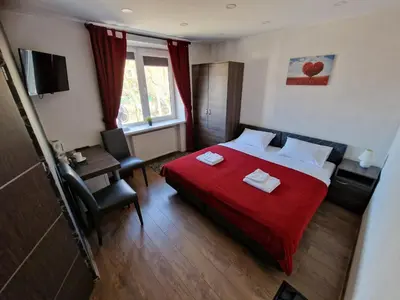 a hotel room with a red bed and a desk at KALIDA Rooms for rent in Raseiniai