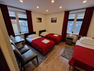 a room with two beds and a chair and a desk at KALIDA Rooms for rent in Raseiniai