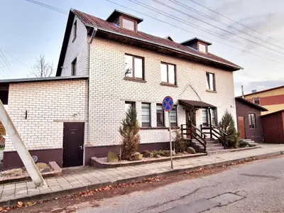 a white brick house on the side of a street at KALIDA Rooms for rent in Raseiniai