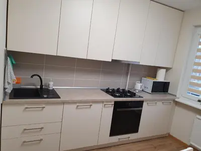 a kitchen with white cabinets and a stove and a sink at Dainai 1-Bedroom apartament. in Šiauliai