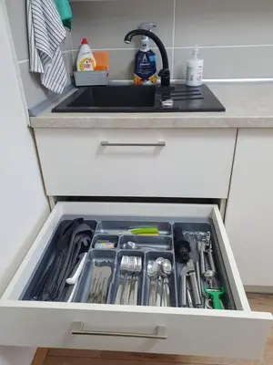 a kitchen drawer filled with utensils and a sink at Dainai 1-Bedroom apartament. in Šiauliai