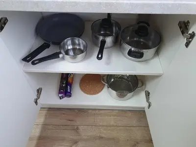 a kitchen shelf with pots and pans on it at Dainai 1-Bedroom apartament. in Šiauliai