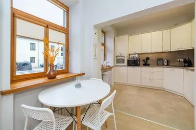 a kitchen with a white table and chairs and a window at Archcathedral apartment by Polo Apartments in Kaunas