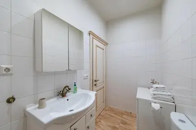 a white bathroom with a sink and a mirror at Archcathedral apartment by Polo Apartments in Kaunas