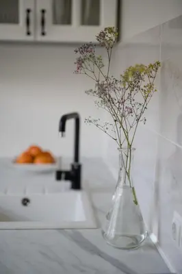 a glass vase with flowers in it on a counter at Nica Apartment in Šiauliai