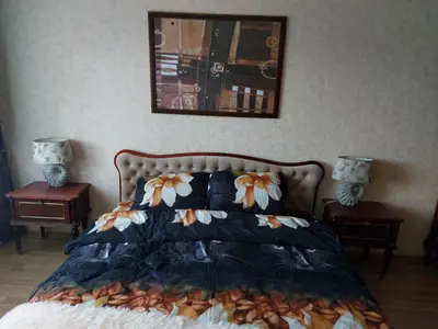 a bedroom with a bed with two nightstands and two lamps at Apartamentai šalia parko in Šiauliai