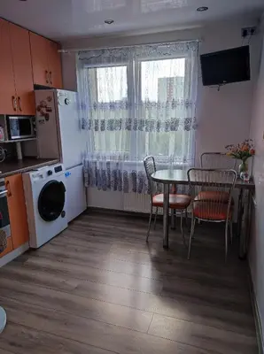 a kitchen with a table and chairs and a window at Apartamentai šalia parko in Šiauliai