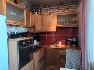 a kitchen with wooden cabinets and a stove top oven at Skaistakalnio apartamentai in Panevėžys
