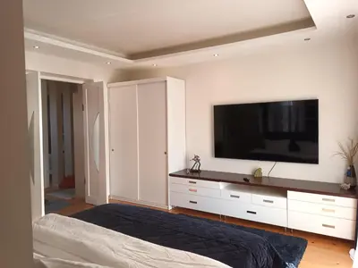 a bedroom with a large television on a white wall at Skaistakalnio apartamentai in Panevėžys