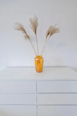an orange vase with feathers in it sitting on a shelf at Archcathedral studio apartment by Polo Apartments in Kaunas