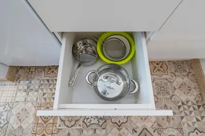 a white drawer with pots and pans in a kitchen at Archcathedral studio apartment by Polo Apartments in Kaunas