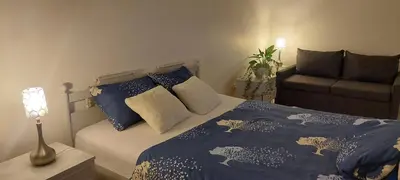 a bedroom with a bed with blue sheets and a couch at Pakeliui in Kaunas