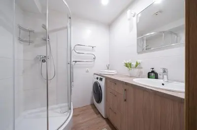 a bathroom with a shower and a sink and a washing machine at Gynėjų Self Check-in Apartments - Lollo Stay in Vilnius