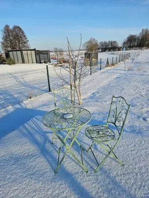 a table and two chairs in the snow at Vaitų Riešutynė - Small shipping container house in Antanava