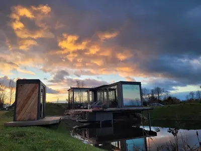 a house sitting on a dock next to a body of water at Vaitų Riešutynė - Small shipping container house in Antanava