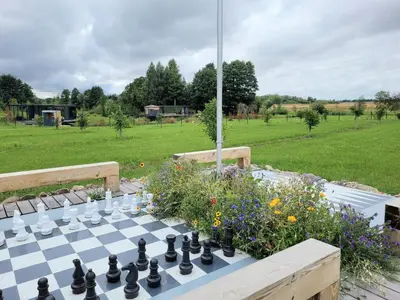 a chess board on a table in a garden at Vaitų Riešutynė - Small shipping container house in Antanava