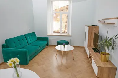 a living room with a green couch and a table at Modern Flat by Lukiskiu square in Vilnius