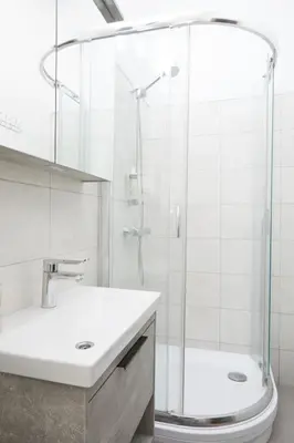 a white bathroom with a shower and a sink at Modern Flat by Lukiskiu square in Vilnius