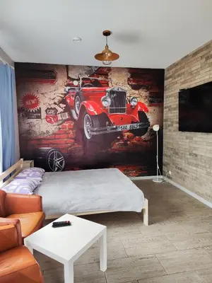 a bedroom with a painting of a car on the wall at Comfort Mile Apartments in Vilnius
