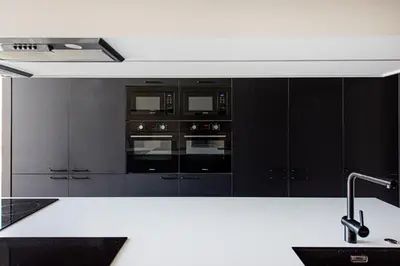 a kitchen with black cabinets and a white counter top at SHED Vilnius Coliving in Vilnius