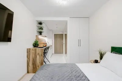 a white bedroom with a bed and a kitchen at Stylish Apartment in Zverynas in Vilnius