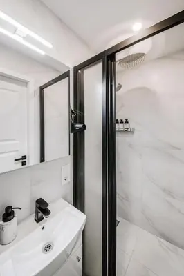 a white bathroom with a shower and a sink at Stylish Apartment in Zverynas in Vilnius