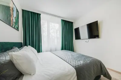 a bedroom with a bed with green curtains and a television at Stylish Apartment in Zverynas in Vilnius