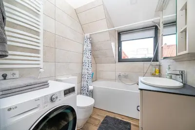 a bathroom with a washer and a toilet and a sink at Cozy Central Attic SELF Check In in Vilnius