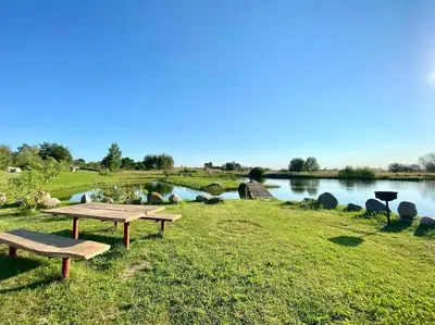 a picnic table in the grass next to a lake at Homestead - Ukmergė area in Pabariškiai