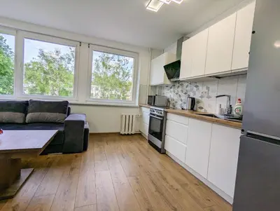 a kitchen and living room with white cabinets and a table at Lovely 2-bedroom flat in the heart of Druskininkai in Druskininkai