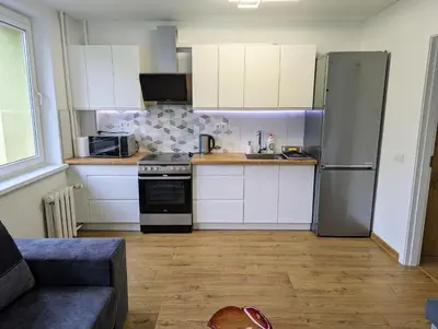 a kitchen with white cabinets and a stainless steel refrigerator at Lovely 2-bedroom flat in the heart of Druskininkai in Druskininkai