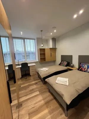 a room with two beds and a desk and a kitchen at Birch Alley Self Check-In in Panevėžys