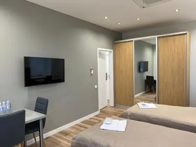 a room with two beds and a table and a television at Birch Alley Self Check-In in Panevėžys