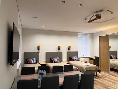 a room with two beds and a table and chairs at Birch Alley Self Check-In in Panevėžys