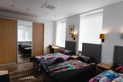 a room with two beds and a living room with windows at Birch Alley Self Check-In in Panevėžys