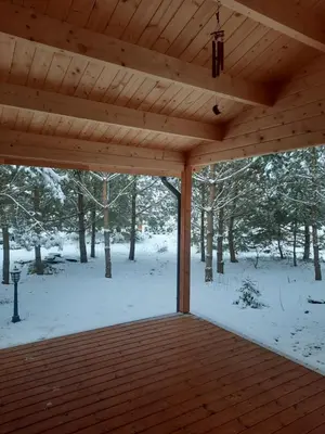 a wooden covered porch with snow on the ground at The Archers House in Viktariškės